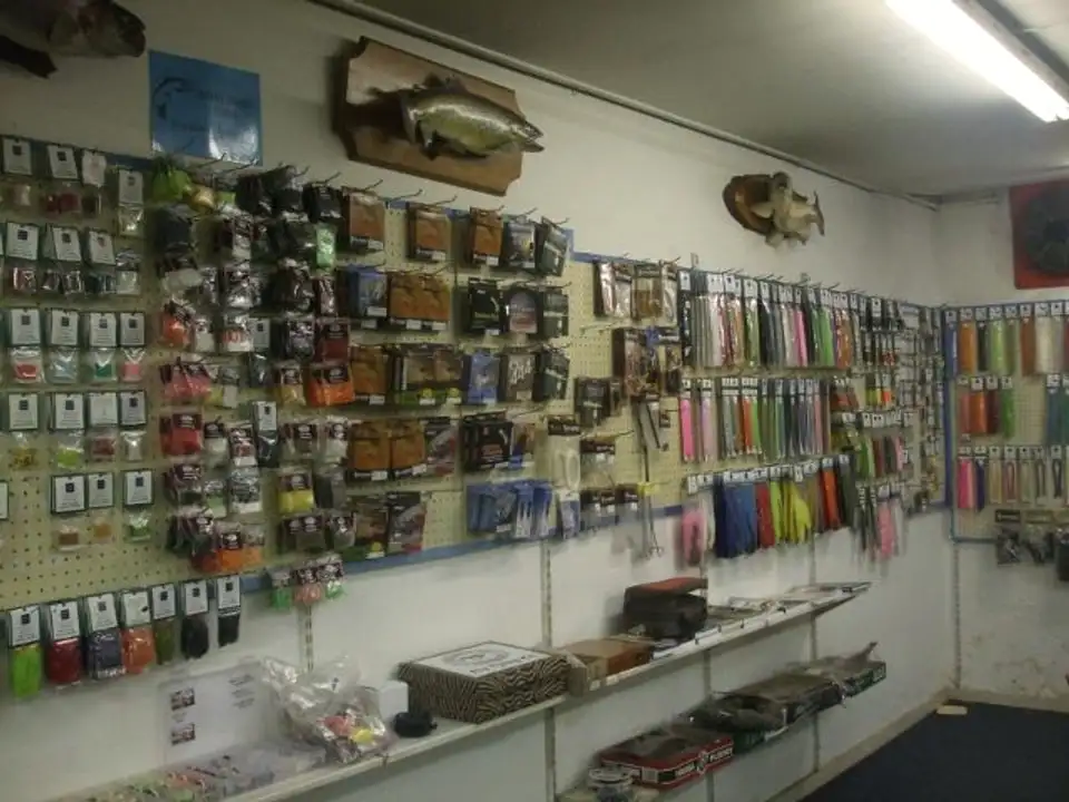 The shop wall of fly tying materials, with mounted fish above