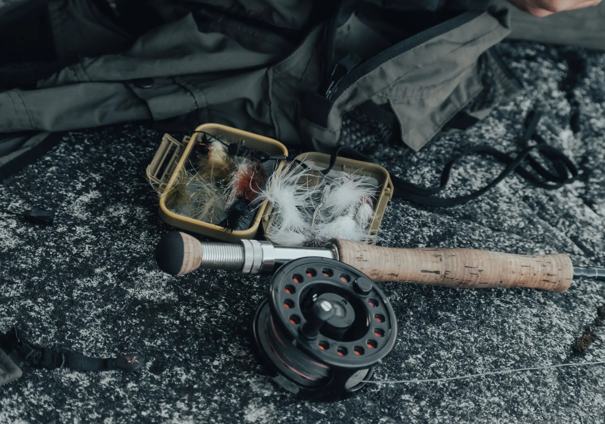 A fly rod, reel and fly box resting on a rock