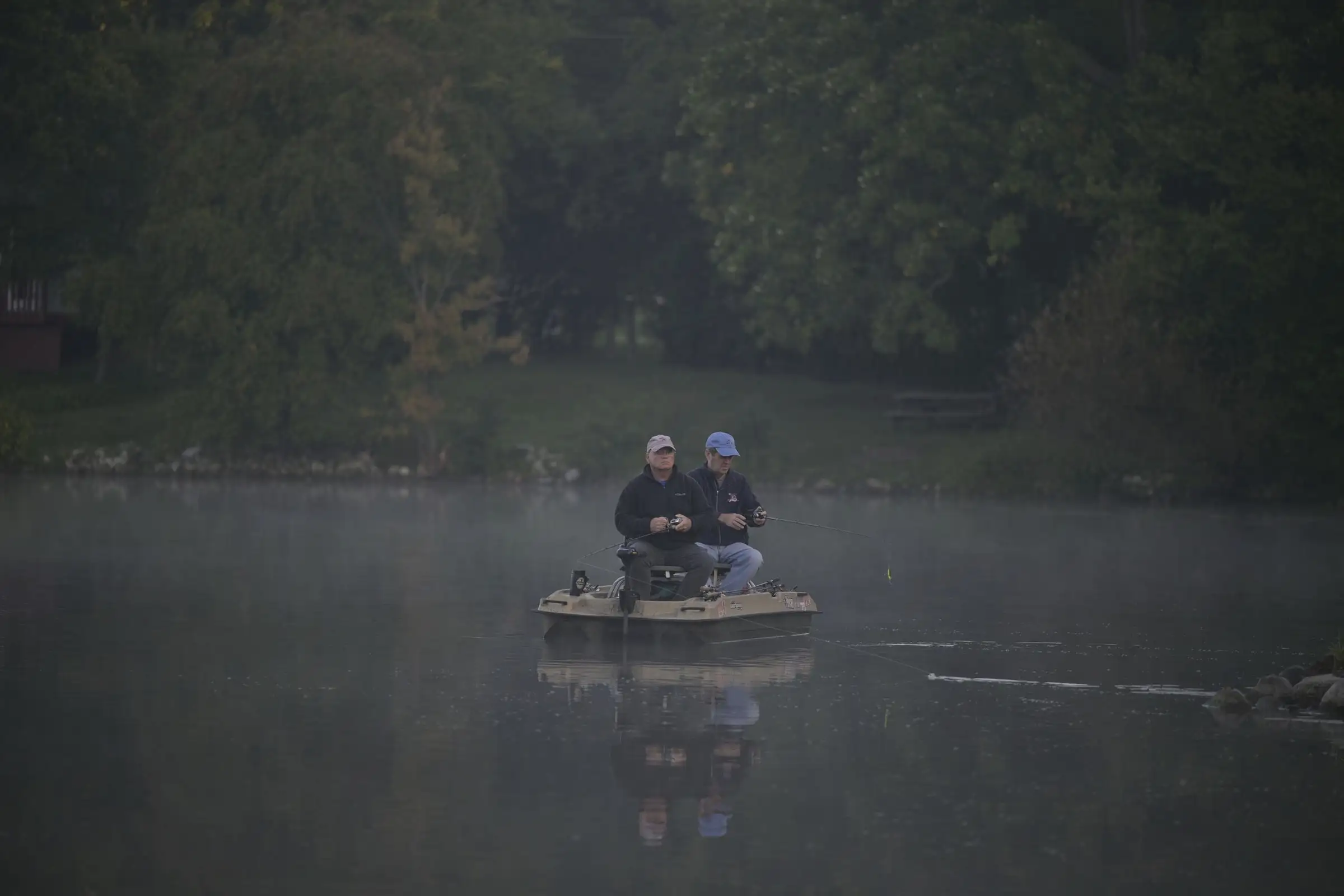 Two anglers in a small boat on a lake in morning mist