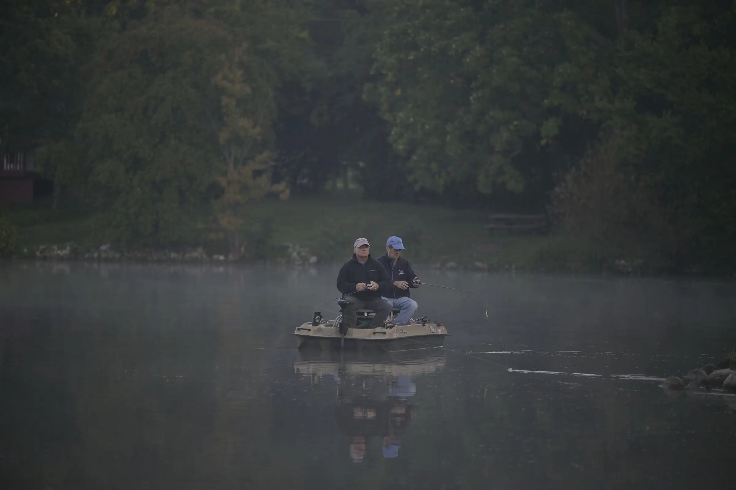 Two anglers in a small boat on a lake in morning mist