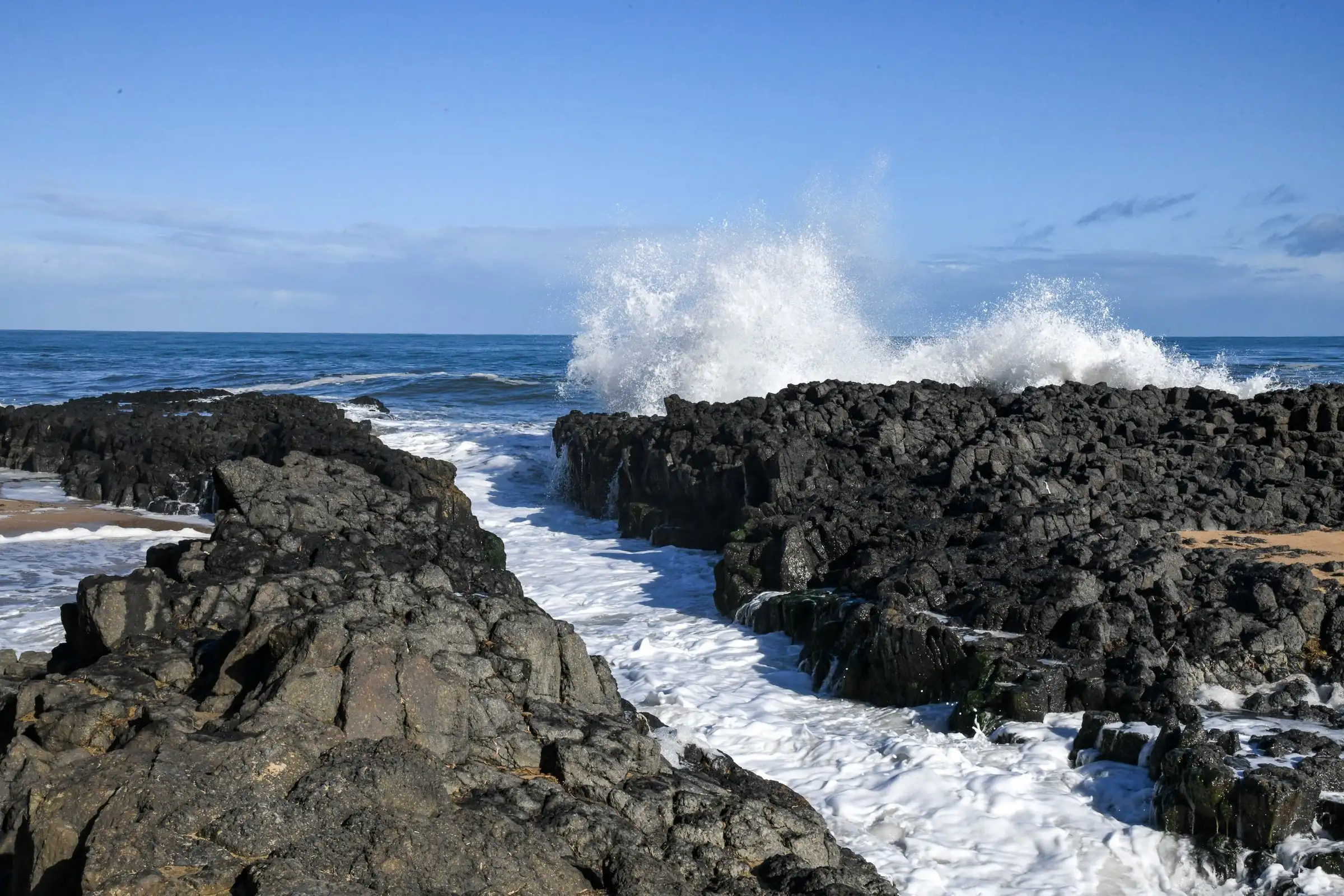 Black rock ledges with a white-water gully running between them