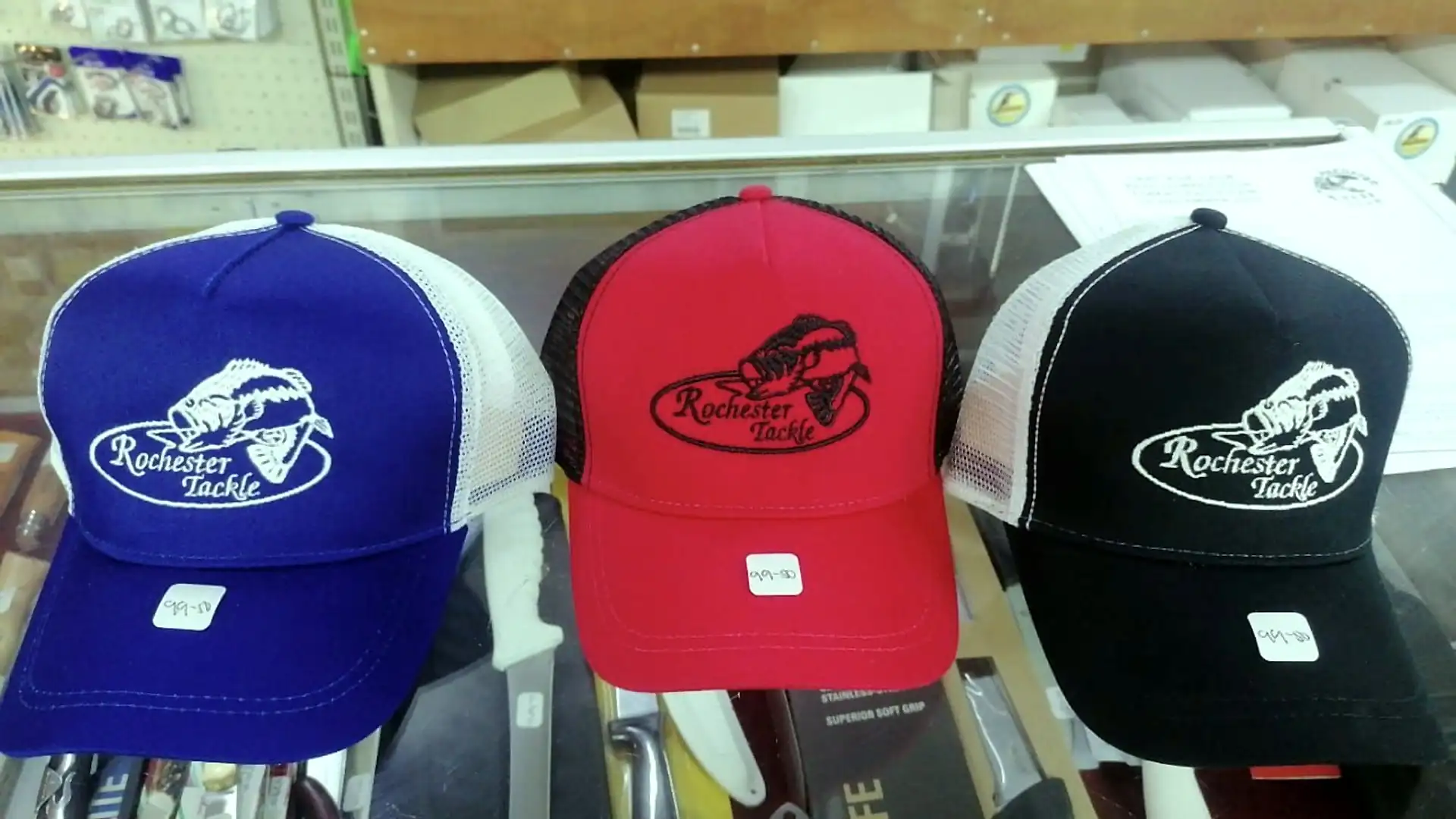 Rochester Tackle caps in blue, red and black on a shelf